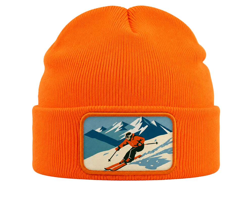 Bright orange ribbed knit beanie with a rectangular patch on the front featuring a retro-style skier in a snowy mountain landscape.